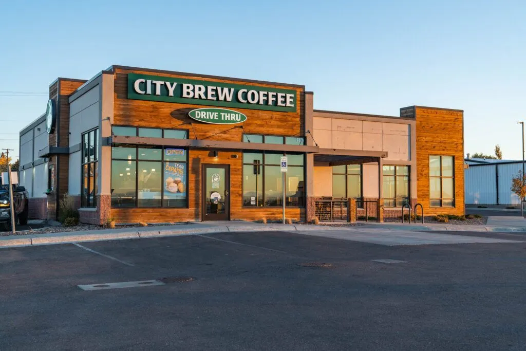 A modern City Brew Coffee shop with large windows, a drive-thru sign, and an empty parking lot on a clear day—an ideal opportunity for anyone seeking Missoula Commercial Real Estate.